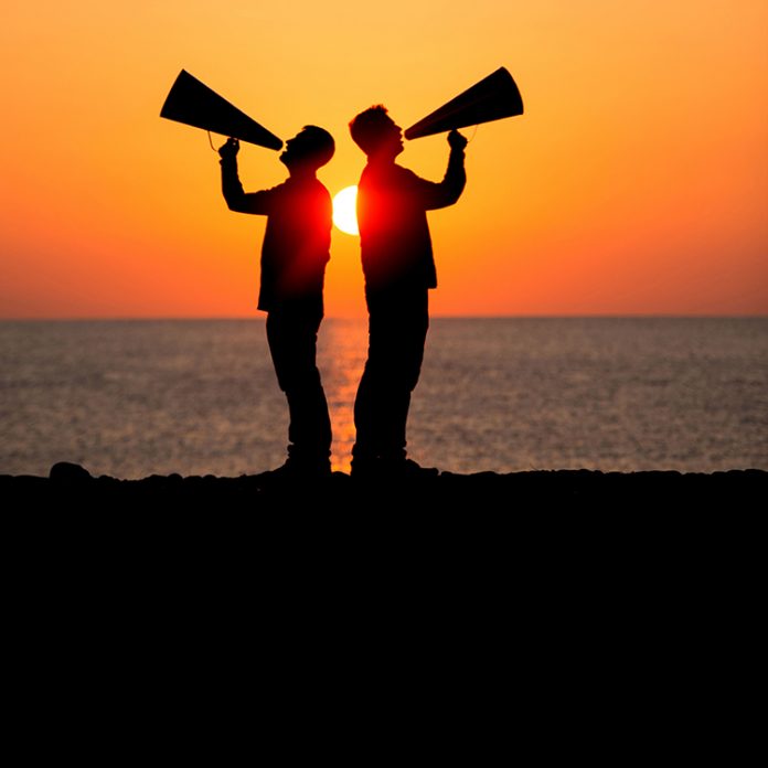 Two males shouting into megaphone at sunrise