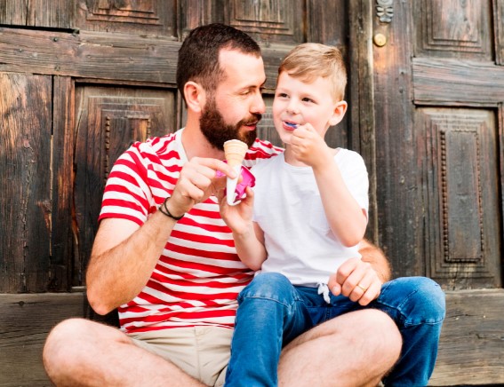 Volwassen man met kleuter op schoot eten samen een ijsje