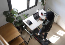 Zelfzorg in supervisie Person multitasking, staying active and focused while working remotely on a laptop at a treadmill desk, blending fitness into a productive home office routine